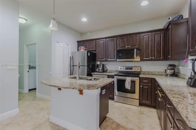 a kitchen with kitchen island granite countertop a sink stove and refrigerator