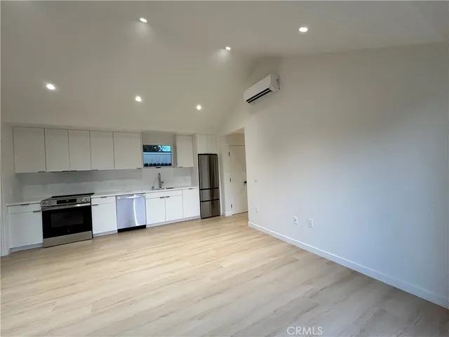 a large kitchen with stainless steel appliances a large counter top a stove a sink and a refrigerator