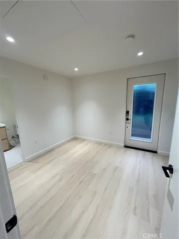 a view of an empty room with wooden floor and closet
