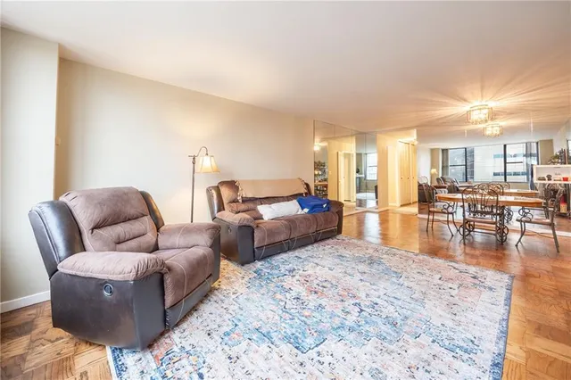 a living room with couches and a dining table with wooden floor