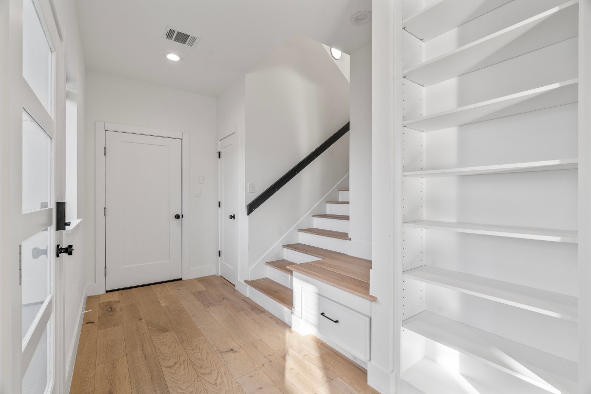 3802 Commerce Street Houston, TX 77003 - Photo 17 of 45 Alternate perspective of the welcoming entry, highlighting built-in storage, a stylish bookcase feature, and access points to the garage, half bath, and staircase leading to the upper level.