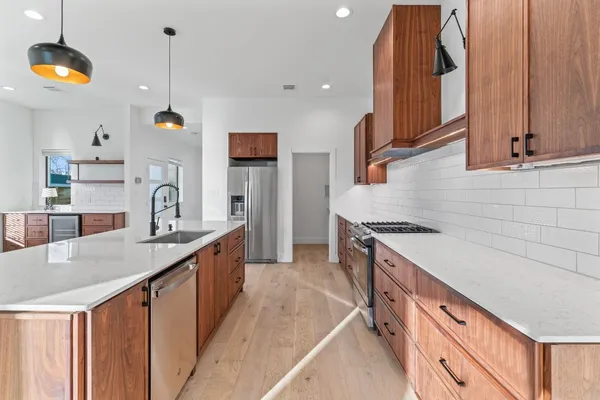 a kitchen with stainless steel appliances granite countertop a sink a stove and a wooden floors