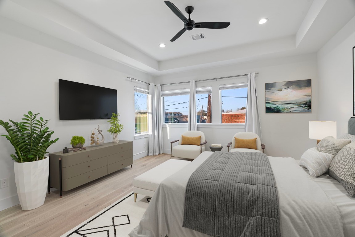 3802 Commerce Street Houston, TX 77003 - Photo 23 of 45 Spacious primary suite designed for comfort and style, featuring high ceilings, a tray ceiling detail, and a modern black fan. Includes a large walk-in closet and direct access to an oversized laundry room with quartz counters, sink, and extra storage for everyday convenience.