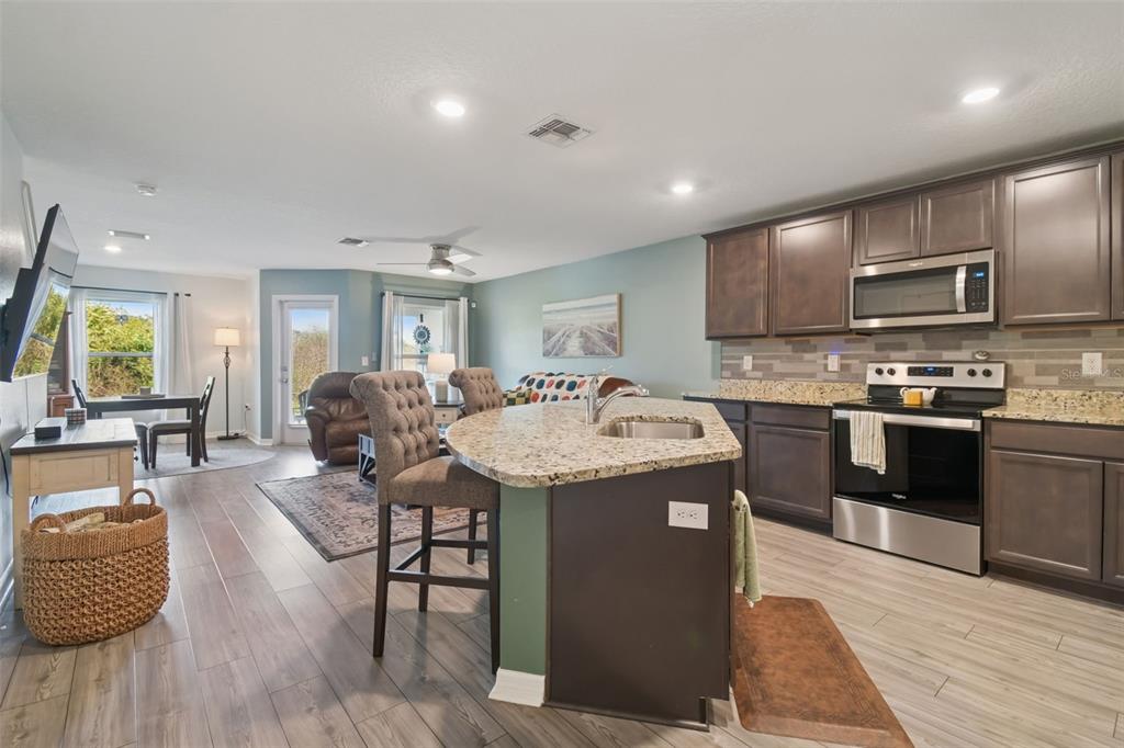 5228 New Friendship Place Tampa, FL 33619 - Photo 5 of 49 a kitchen with stainless steel appliances kitchen island granite countertop a sink dishwasher a stove and a refrigerator with wooden floor