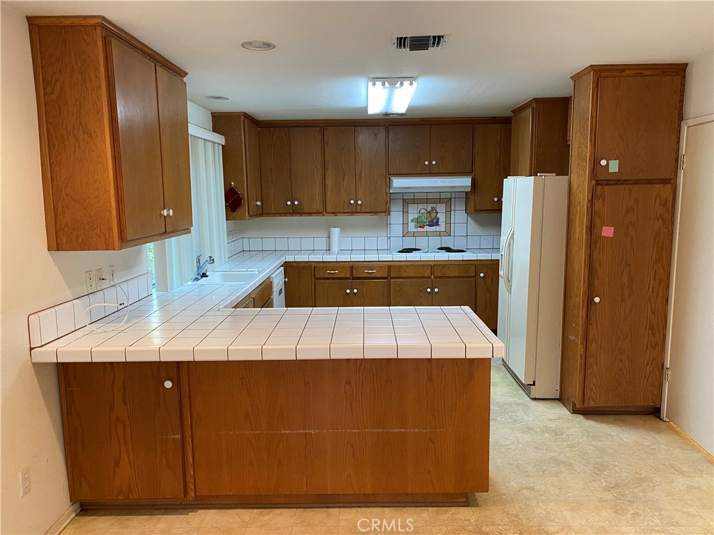 12671 Daryl Avenue Granada Hills, CA 91344 - Photo 6 of 10 a kitchen with kitchen island cabinets and refrigerator