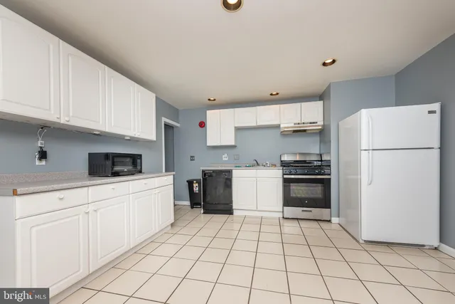 a kitchen with white cabinets a refrigerator and a stove top oven