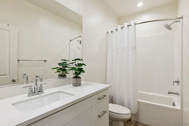 a bathroom with a granite countertop sink a toilet and shower