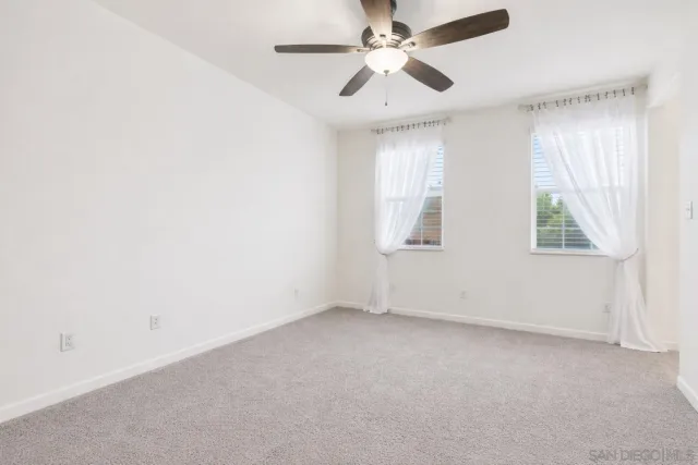 an empty room with windows and fan