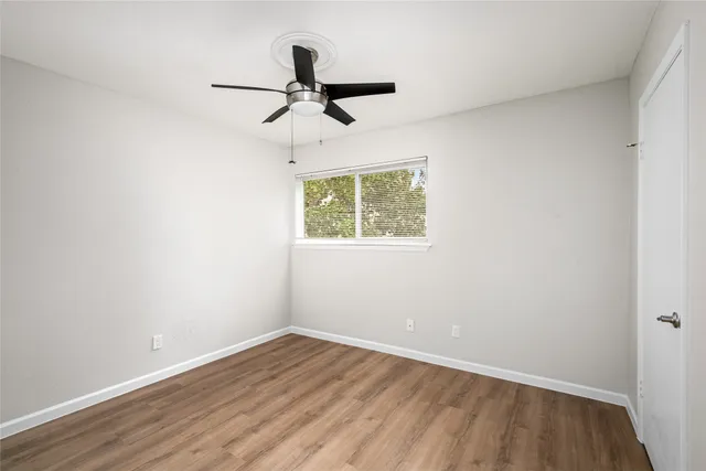 a view of a room with wooden floor ceiling fan and window