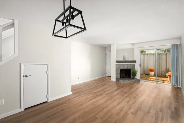 an empty room with wooden floor fireplace and windows