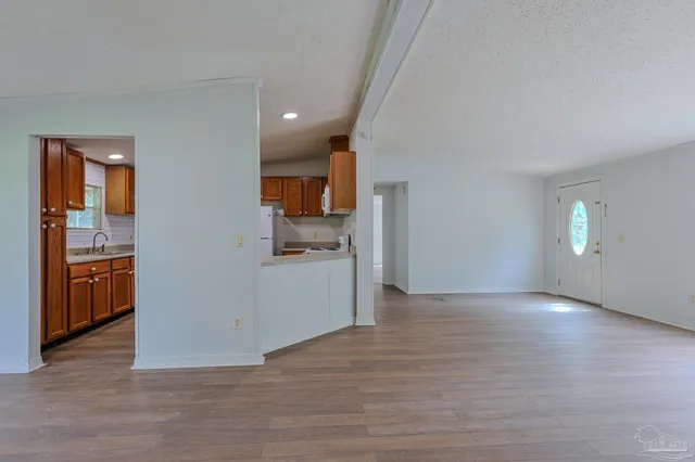 a view of a kitchen with a sink stove cabinets and empty room