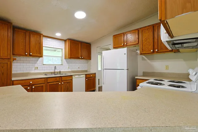 a kitchen with stainless steel appliances granite countertop a refrigerator stove a sink dishwasher and wooden cabinets