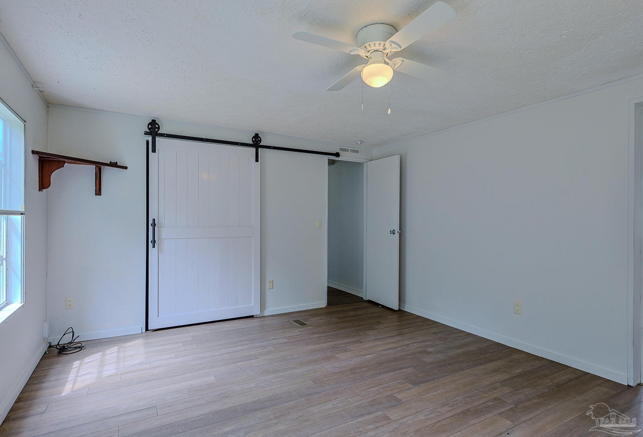 6850 Bratt Road Century, FL 32535 - Photo 42 of 57 a view of an empty room with a ceiling fan and wooden floor
