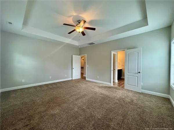 an empty room with windows and fan