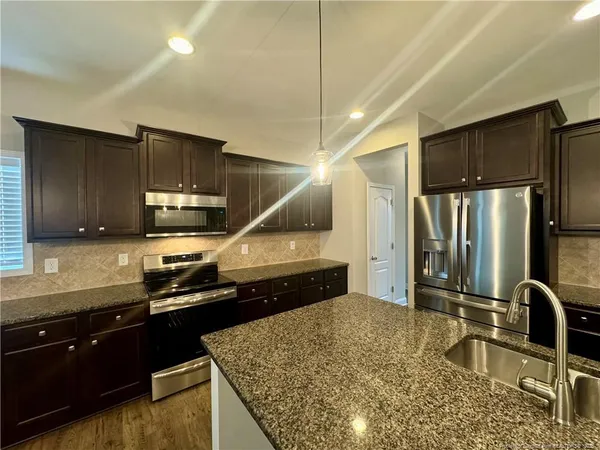 a kitchen with kitchen island granite countertop a sink stainless steel appliances and cabinets