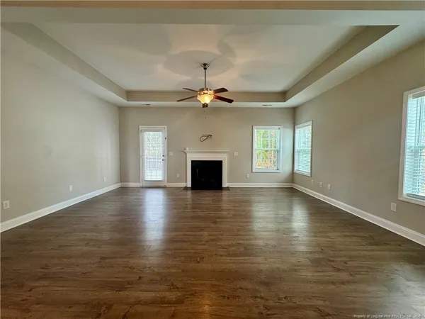 an empty room with wooden floor fireplace and windows