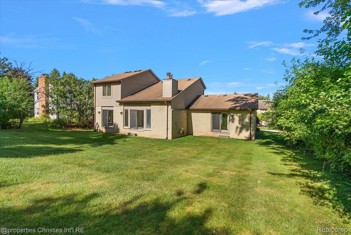 37224 Chesapeake Road Farmington, MI 48335 - Photo 11 of 50 Spacious rear yard with a neutral-toned exterior, multiple large windows, a sliding glass door, and established perimeter shrubbery