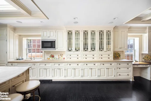 a large white kitchen with granite countertop a sink and white cabinets with wooden floor