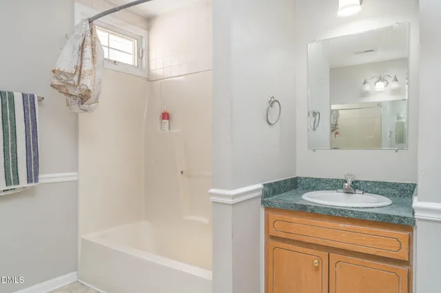 a bathroom with a granite countertop sink a mirror and a bathtub