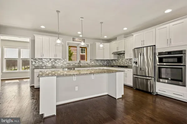 a kitchen with kitchen island granite countertop a sink a counter space appliances and cabinets