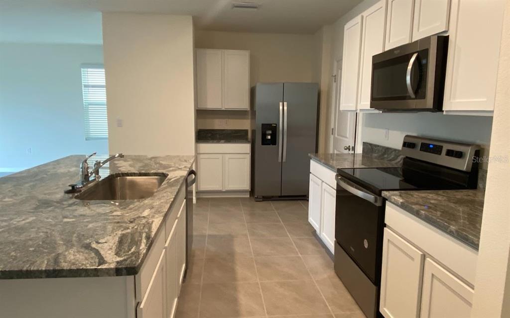 8309 Hardy Bay Loop Wesley Chapel, FL 33545 - Photo 3 of 24 a kitchen with stainless steel appliances granite countertop a sink stove and refrigerator