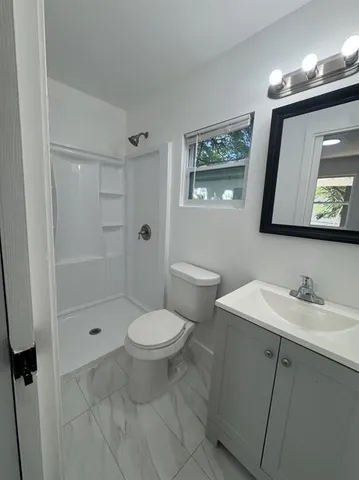 a bathroom with a toilet a sink a mirror a vanity and shower