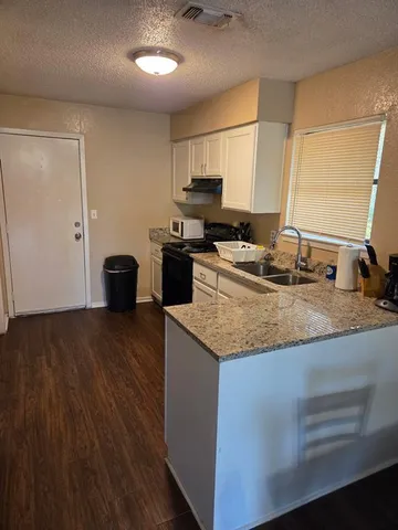 a kitchen with granite countertop a sink stove and refrigerator