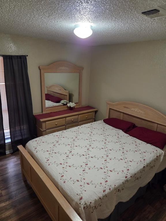 744 Sycamore Street, Unit 74 Paris, TX 75460 - Photo 8 of 10 a bedroom with a bed and a dresser with wooden floor