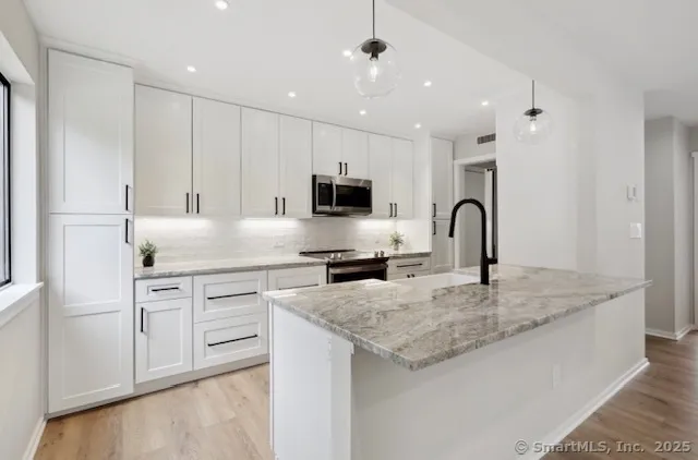 a kitchen with granite countertop white cabinets and stainless steel appliances