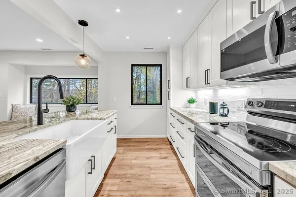 a large kitchen with stainless steel appliances granite countertop a lot of counter space and wooden floor