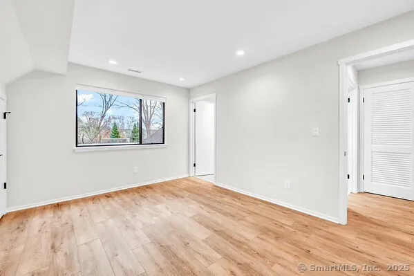 a view of an empty room with wooden floor and window