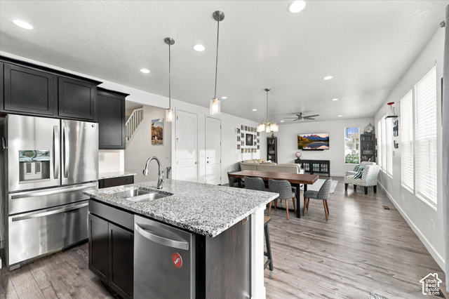 972 Vine Street Mapleton, UT 84664 - Photo 10 of 40 Open-concept living area featuring wood-finish flooring, a kitchen island with granite countertops, stainless steel appliances, recessed lighting, and ample natural light from multiple windows