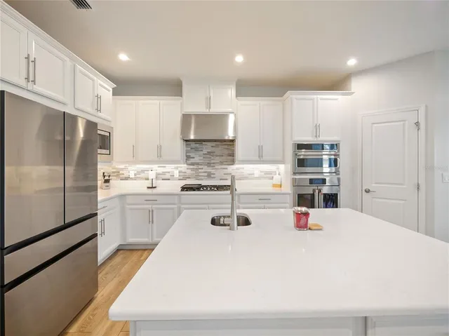a large kitchen with stainless steel appliances kitchen island granite countertop a large center island and a sink