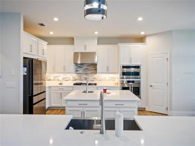 a living room with furniture kitchen view and a wooden floor