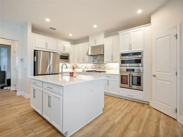 a kitchen with stainless steel appliances granite countertop a sink a stove a refrigerator and cabinets