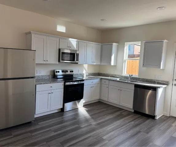 a kitchen with granite countertop a refrigerator stove top oven and sink