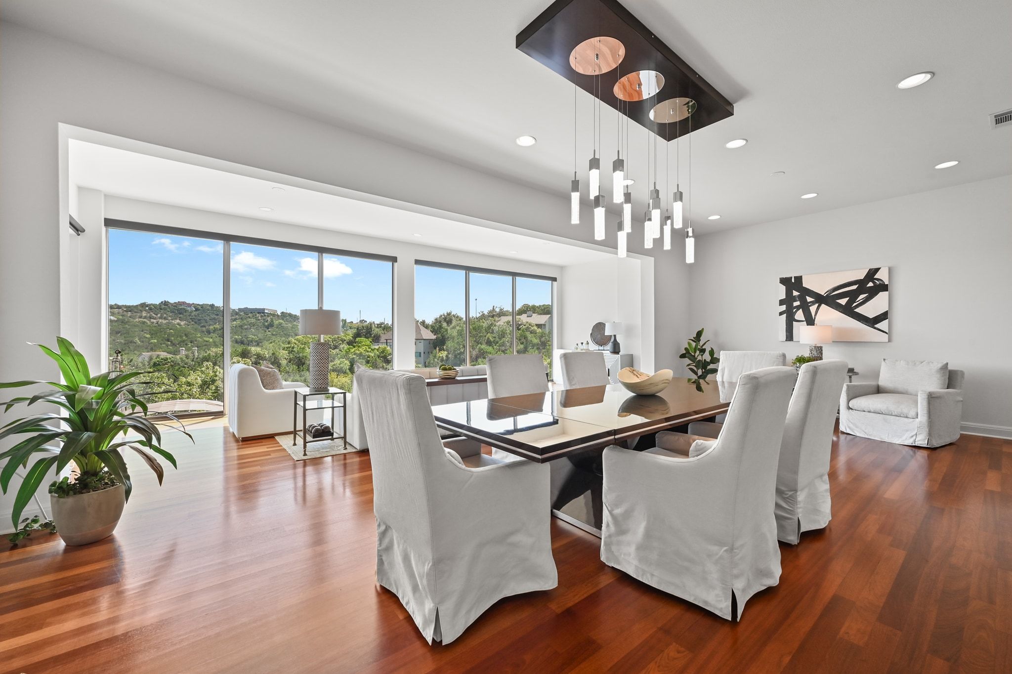 405 Barrett Lane Austin, TX 78733 - Photo 6 of 37 a dining room with wooden floor a chandelier a glass table and chairs