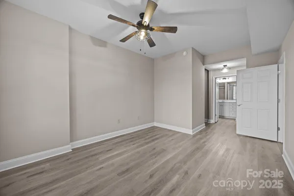 an empty room with wooden floor and a ceiling fan