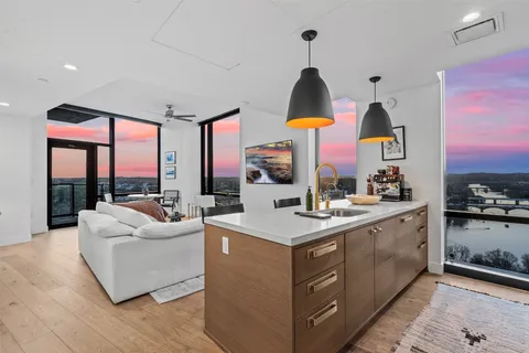 a kitchen with a stove a sink and a living room with a large window