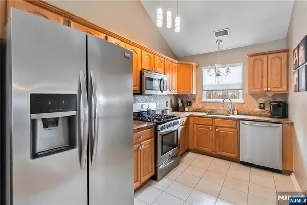 a kitchen with stainless steel appliances granite countertop a refrigerator a sink a stove top oven and a window