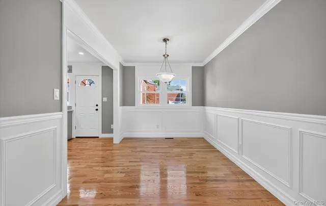 a view of a hallway with wooden floor and chandelier