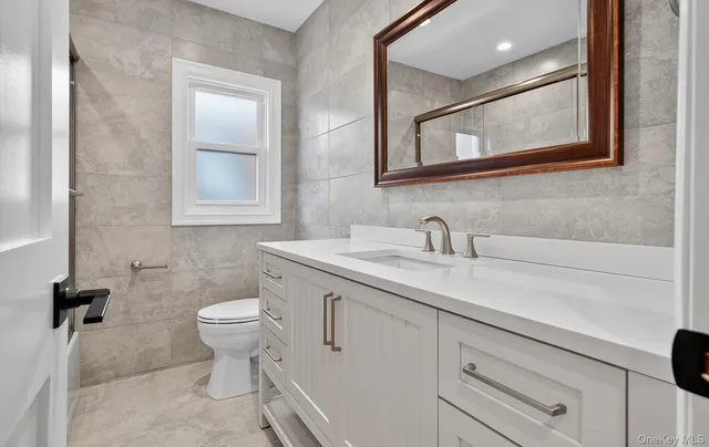 a bathroom with a toilet sink a mirror and vanity