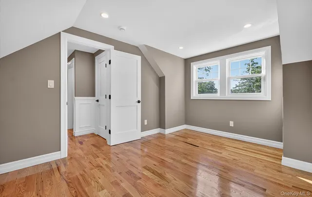 a view of empty room with wooden floor and window
