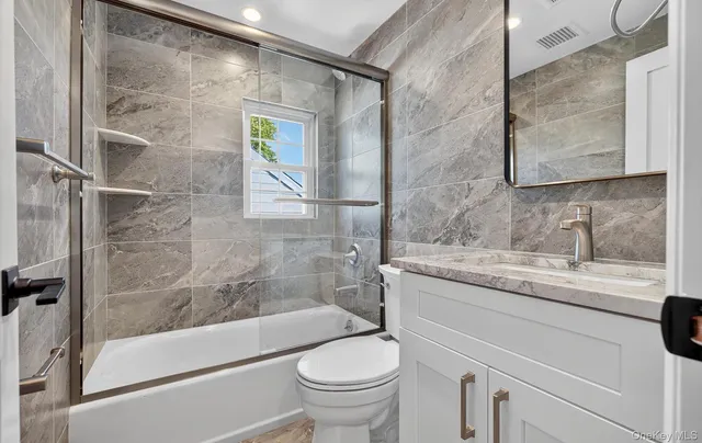 a bathroom with a granite countertop sink a toilet and shower