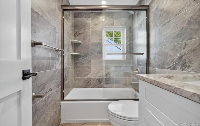 a bathroom with a granite countertop bathtub shower sink vanity and toilet