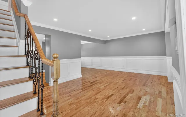 a view of an empty room with wooden floor and stairs