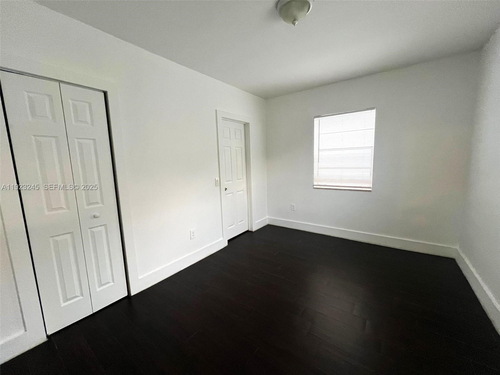 1040 Northwest 3rd Avenue, Unit 7 Miami, FL 33136 - Photo 12 of 15 an empty room with wooden floor and windows