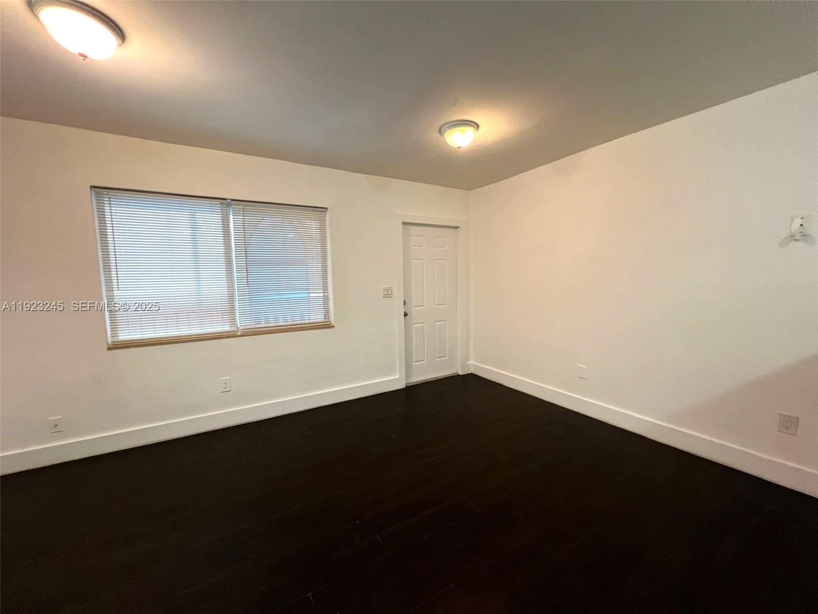 1040 Northwest 3rd Avenue, Unit 7 Miami, FL 33136 - Photo 13 of 15 a view of an empty room with wooden floor and a window