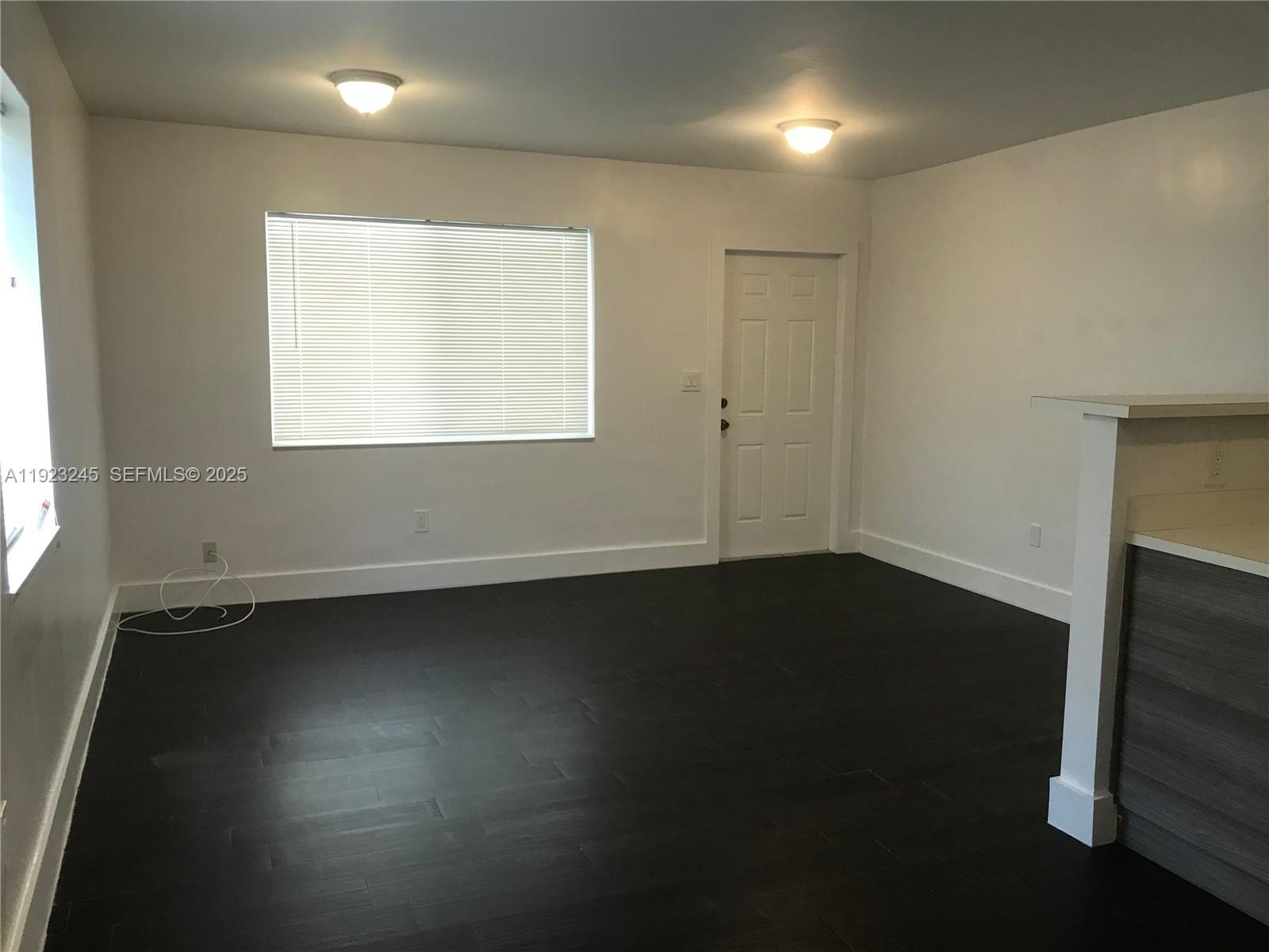 1040 Northwest 3rd Avenue, Unit 7 Miami, FL 33136 - Photo 6 of 15 an empty room with wooden floor and windows