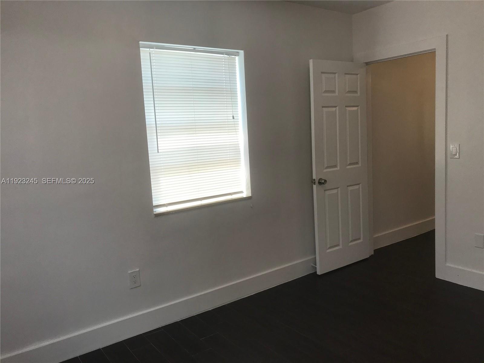 1040 Northwest 3rd Avenue, Unit 7 Miami, FL 33136 - Photo 10 of 15 a view of an empty room with wooden floor and a window